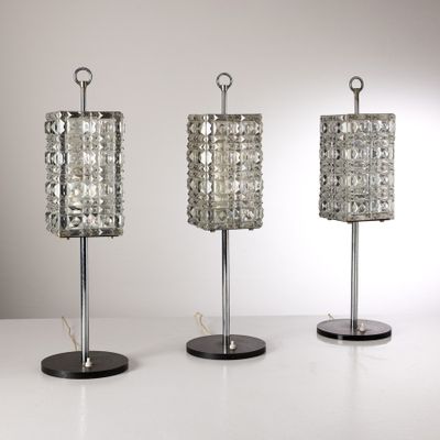 trois lampes de table en verre posées sur une surface blanche, sur fond blanc