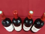 quatre bouteilles de vin sont alignées sur un support rouge
