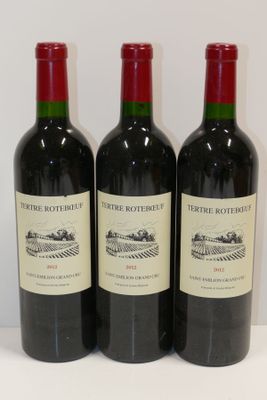trois bouteilles de vin rouge sont alignées sur une table