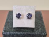 une paire de boucles d'oreilles en tanzanite posées sur un bloc de marbre
