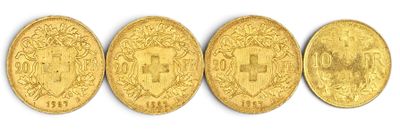 quatre pièces d'or sont alignées sur une surface blanche