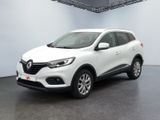 Une voiture blanche est garée dans une pièce blanche au sol noir.