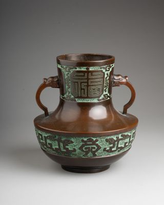 a brown and green vase sitting on a table