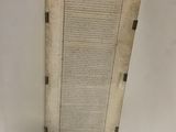 un vieux livre posé sur une table à côté d'un mur blanc