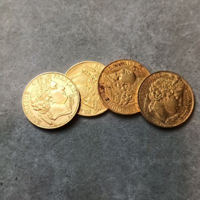 Quatre pièces d'or sont posées les unes à côté des autres sur une table.