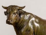 a statue of a bull that is standing in front of a white wall