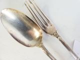 deux cuillères en argent et une fourchette sur une table blanche