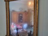 a mirror on the wall above a table with blue vases