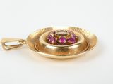 a close up of a gold plate with a pink stone in it