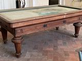 une table de billard avec un plateau en verre posée sur un sol en briques