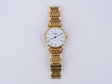gros plan d'une montre-bracelet en or sur une surface blanche