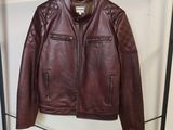 une veste en cuir marron suspendue à un porte-manteau dans une pièce