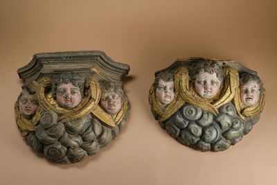pair of decorative wall plaques with faces on them on a beige background