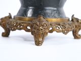 a black and gold vase on a stand on a white surface