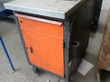 a metal table with an orange cabinet next to a metal table