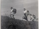 black and white photograph of a group of people with backpacks running up a hill