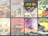 Plusieurs albums de BD sont alignés sur une surface bleue