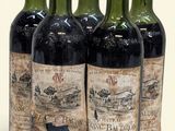 quatre bouteilles de vin sont alignées sur une surface blanche