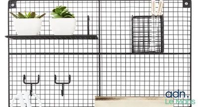 une étagère en fil de fer noir sur laquelle sont posés des pots et des plantes