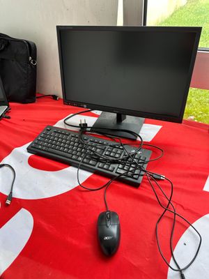 a desk with a computer, keyboard, mouse, and bag on it