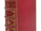 un vieux livre avec une couverture rouge et des bordures dorées sur fond blanc