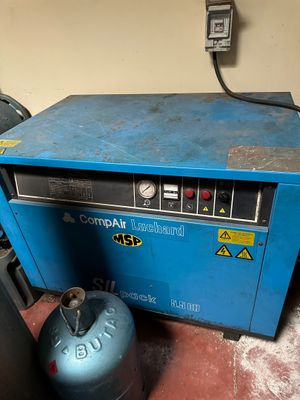 an image of a blue machine sitting in a room next to a gas can