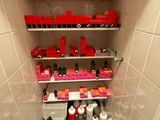 une petite salle de bains avec des toilettes et une étagère remplie de produits de beauté