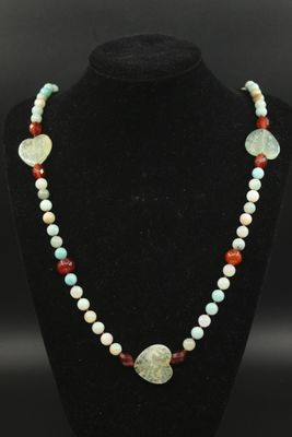 un collier de perles orné d'un pendentif en pierre verte, rouge et blanche