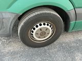 a green bus with black dots on the tire