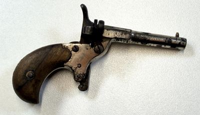 un pistolet posé sur une surface blanche, avec un fond blanc