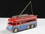 un petit bus rouge et bleu posé sur une surface blanche