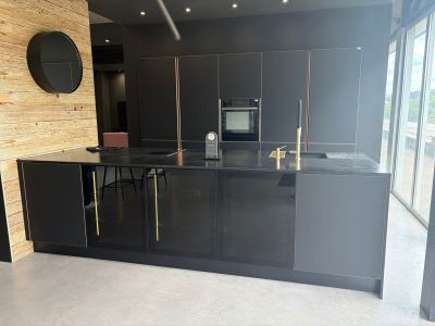 une grande cuisine avec un plan de travail noir et des placards noirs