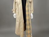a mannequin wearing a beige trench coat and black dress