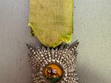 silver medal with a yellow ribbon on top of a metal surface