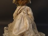 an old fashioned teddy bear dressed in a white dress and hat