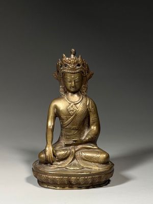 une statue en or représentant un Bouddha assis sur un socle blanc