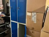 une pile de cartons posée par terre à côté d'un casier bleu