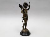 une statue en bronze représentant un Cupidon tenant un oiseau, posée sur un socle