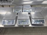 four electronic scales are on a table in a warehouse