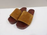 the brown and tan slippers are on a white surface