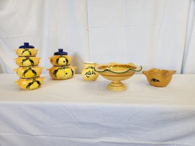 a lot of yellow vases on a table with a white table cloth