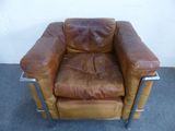 brown leather chair with metal legs and armrests in front of a white wall