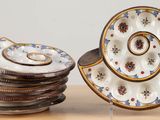 une pile d'assiettes posée sur une table, à côté d'une assiette ornée d'un motif en spirale