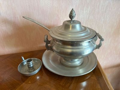 a silver plate with a silver lid and a spoon on a wooden table