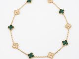 a gold and green bracelet with four clover charms