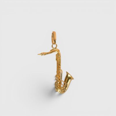 un gros plan d'un pendentif en forme de saxophone doré sur fond blanc