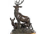 une statue en bronze représentant un cerf et deux biches, posée sur un socle en marbre