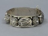 a close up of a silver bracelet on a gray surface