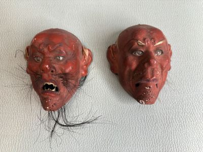 une paire de masques rouges avec des cheveux sur un fond blanc