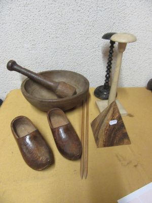 a table with a bowl, a pair of wooden shoes and a pair of wooden spoons on it